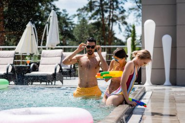 Genç çoklu etnik arkadaşlar tatil köyünde yüzüyorlar.
