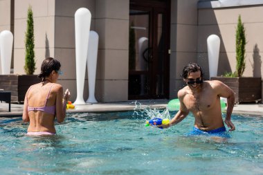 Genç arkadaşlar tatil köyünde yüzme havuzunda vakit geçiriyorlar.