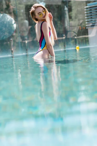 水泳プールに立つサングラスのきれいな女性の表面レベル — ストック写真
