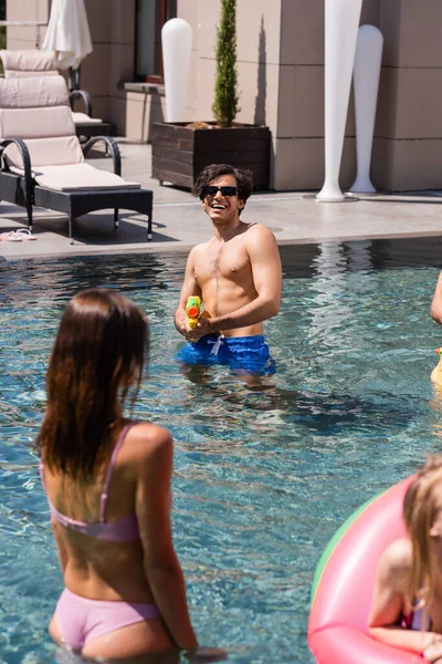 Homem Alegre Brincando Com Pistola Água Perto Mulheres Piscina — Fotografia de Stock