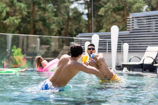 Young Interracial Men Having Water Pistols Battle Swimming Pool — Stock Photo, Image