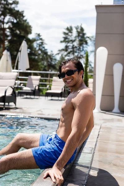 Vista De Ángulo Alto Del Hombre Con Gafas De Sol Sonriendo Mientras Se  Relaja En La Piscina Cerca Del Jugo De Naranja Fotos, retratos, imágenes y  fotografía de archivo libres de derecho.