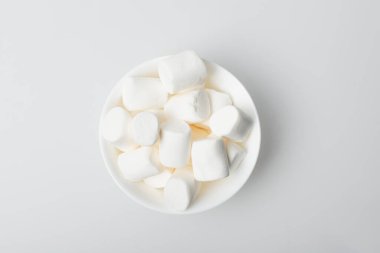 top view of soft and puffy marshmallows in bowl on white clipart