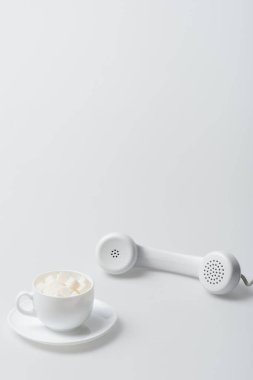 Şeker küpleri fincanda, çay tabağı da beyaz retro telefonun yanında.