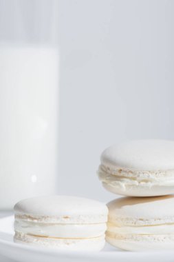Beyaz üzerine izole edilmiş bulanık süt bardağının yakınındaki lezzetli badem kurabiyelerinin yakın görüntüsü.