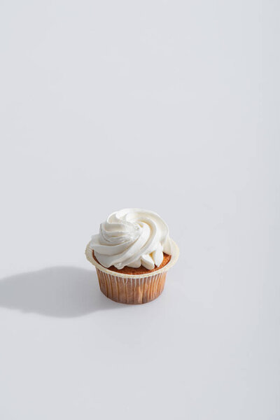shadow near tasty cupcake with icing on top on white 