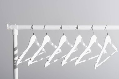 collection of white hangers on clothes rack isolated on grey clipart