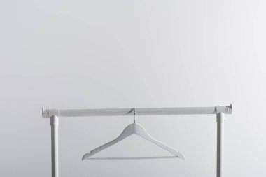single white hanger on garment rack isolated on grey clipart