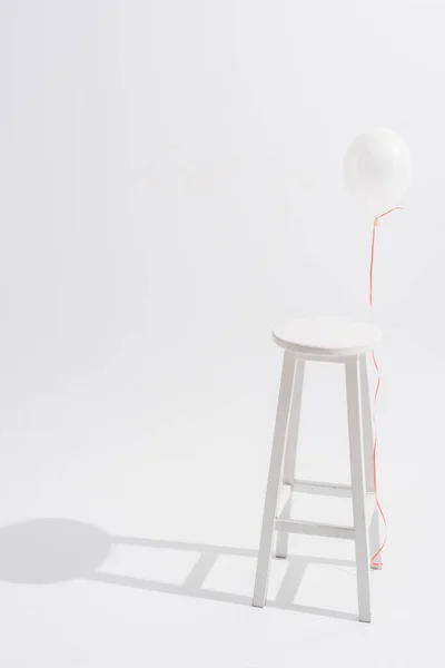 白色背景的高木制凳子旁边的气球 — 图库照片
