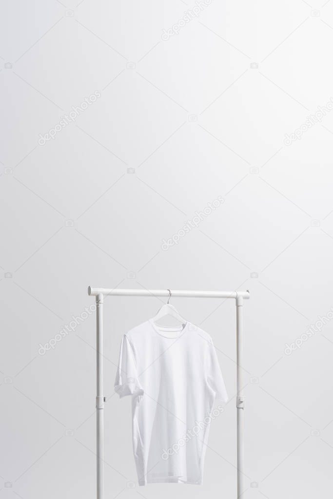 white t-shirt hanging on clothes rack isolated on grey 