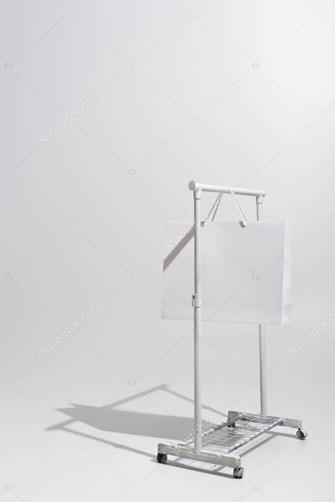 shopping bag hanging on garment rack on grey