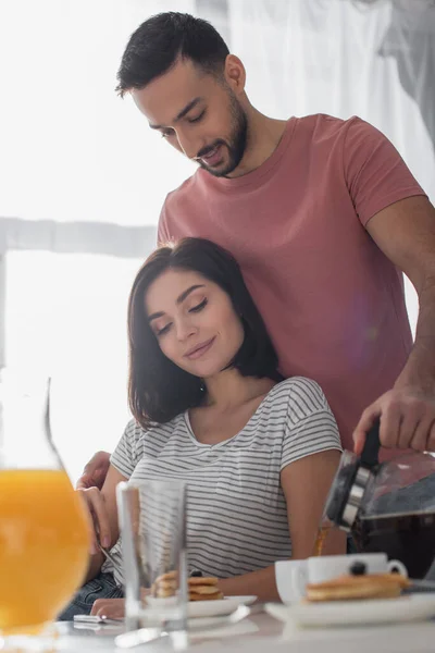 Glimlachende Jonge Man Knuffelen Vriendin Met Ontbijt Gieten Koffie Van — Stockfoto