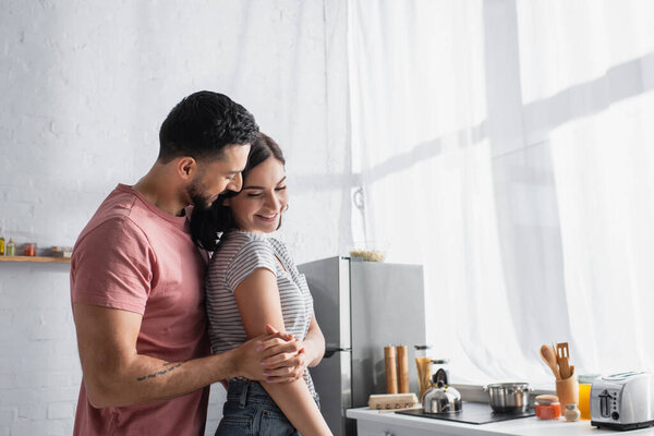 smiling young couple in love gently hugging in kitchen