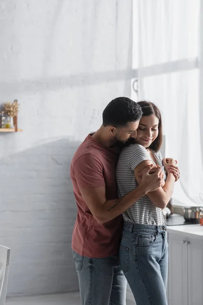 Sonriente Joven Pareja Ropa Casual Abrazándose Cocina Moderna —  Fotos de Stock