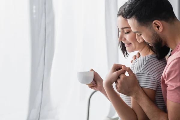 Sorrindo Jovem Com Xícara Café Tocando Mãos Com Namorado Cozinha — Fotografia de Stock