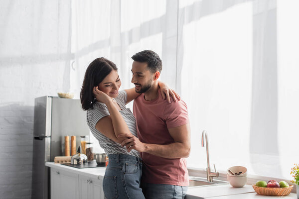 cheerful young couple hugging in modern bright kitchen