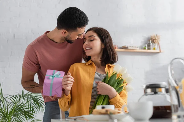 Souriant Jeune Homme Présentant Boîte Cadeau Petite Amie Avec Bouquet — Photo