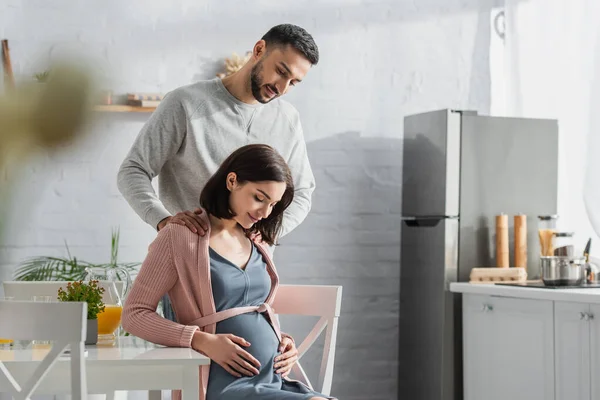 Smiling Young Man Holding Hands Shoulders Pregnant Woman Kitchen — 스톡 사진