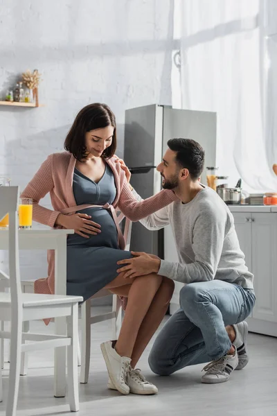 Positive Young Man Sitting Knee Pregnant Woman Kitchen — 스톡 사진