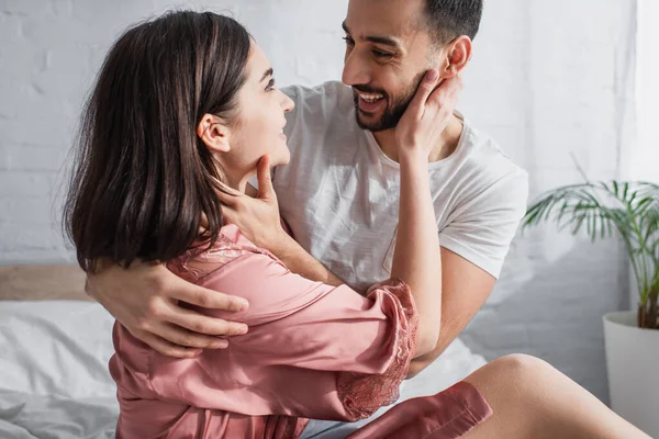 Jovem Sorridente Gentilmente Abraçando Tocando Rosto Namorada Peignoir Quarto — Fotografia de Stock