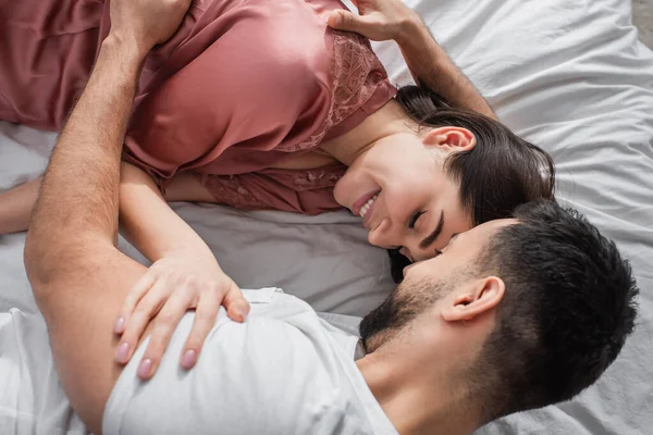 若い男がベッドの上に横になって白いリネンと優しく抱擁のガールフレンドでベッドルーム — ストック写真