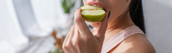 cropped view of young woman biting apple, banner