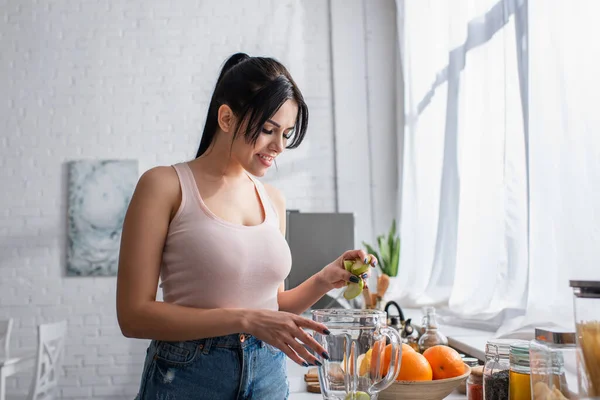 快乐的年轻女人把切好的苹果放在搅拌机上 — 图库照片