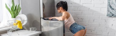 Esmer ve seksi kadın buzdolabının üzerine eğilmiş, afiş