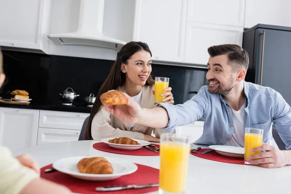 Alegre Hombre Dando Croissant Borrosa Hija Cerca Sonriente Esposa Durante — Foto de Stock