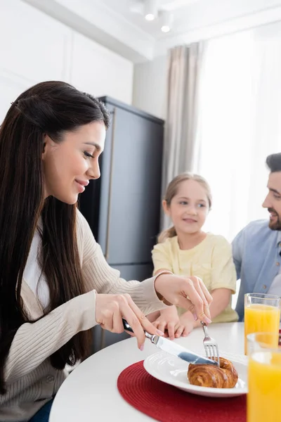 Smiling Woman Cutting Croissant Blurred Husband Daughter Breakfast — Stock Photo, Image