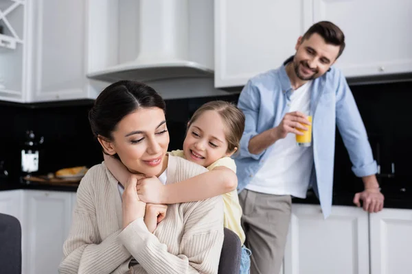 Enfant Embrassant Maman Heureuse Près Papa Debout Avec Jus Orange — Photo