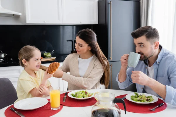 Cheerful Girl Holding Croissant Parents Vegetable Salad Breakfast — Stock Photo, Image