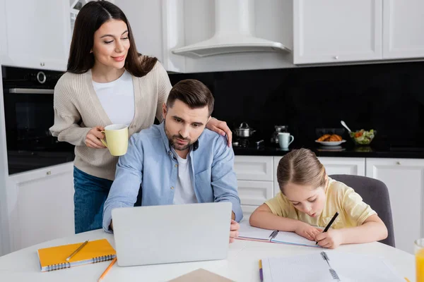 Glad Kvinna Tittar Dotter Skriva Anteckningsbok Medan Gör Läxor Nära — Stockfoto