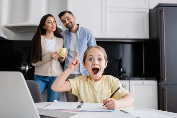 Upphetsad Flicka Visar Idé Gest Nära Föräldrar Ler Suddig Bakgrund — Stockfoto