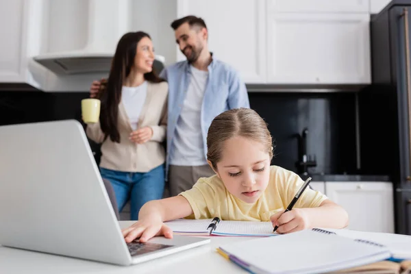 Enfant Utilisant Ordinateur Portable Écrivant Dans Cahier Près Parents Souriants — Photo