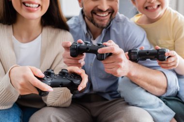 KYIV, UKRAINE - 8 Nisan 2021: Gülümseyen ailenin elindeki joysticklerin seçici odak noktası, kırpık görüş
