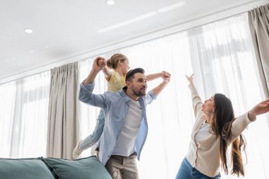 happy family imitating flying while having fun at home clipart