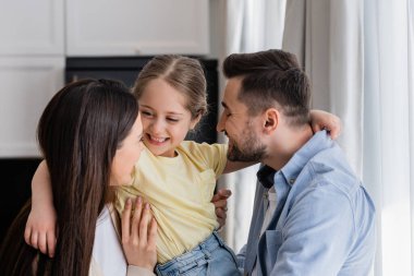 Mutlu ebeveynler, neşeli kızları ellerinde tutuyorlar.