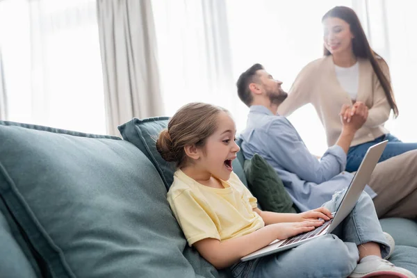 Excited Girl Using Laptop Happy Parents Holding Hands Talking Blurred — Stock Photo, Image