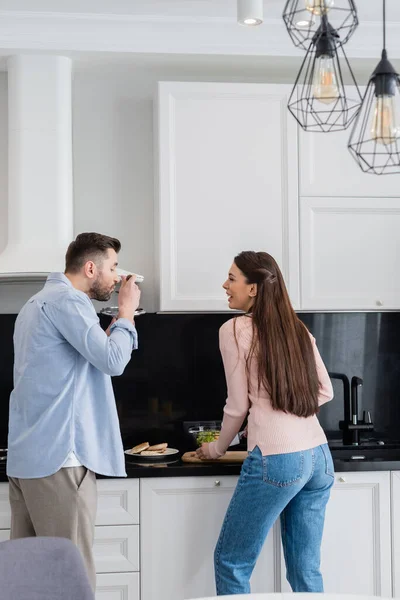 Homem Com Panela Tampa Degustação Refeição Perto Rindo Esposa Cozinha — Fotografia de Stock