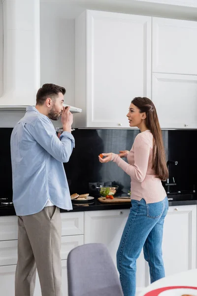 Γυναίκα Μιλάει Τον Σύζυγο Δοκιμάζοντας Γεύμα Στην Κουζίνα — Φωτογραφία Αρχείου