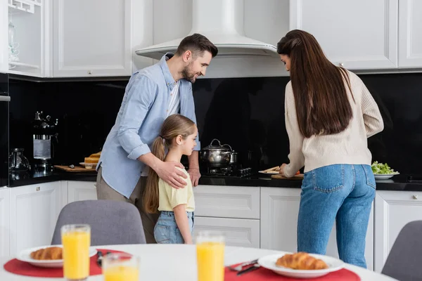 Hombre Con Hija Mirando Esposa Preparando Desayuno Cerca Jugo Naranja — Foto de Stock