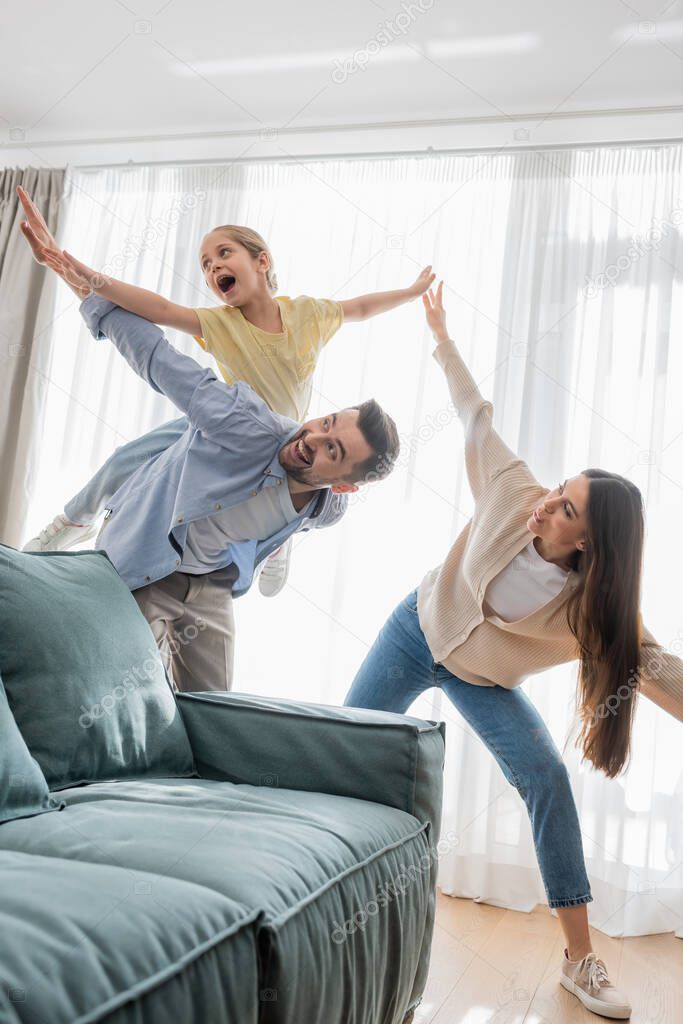 cheerful family having fun while imitating flying at home