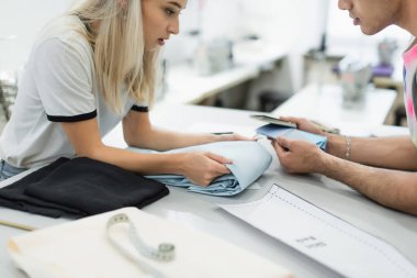 Dikiş deseni yakınındaki doku ve renk paletine bakan tasarımcıların kırpık görünümü, bulanık ön plan
