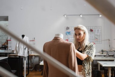 Atölyedeki genç, sarışın moda tasarımcısı.