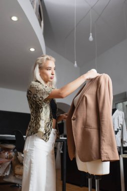 stylish fashion designer standing near blazer on mannequin clipart