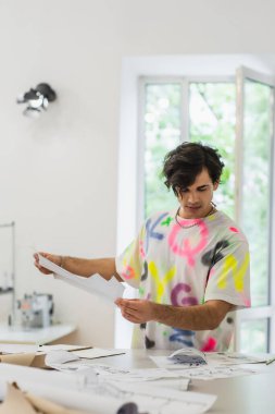Yaratıcı moda tasarımcısı terzi dükkanında çalışırken dikiş desenini tutuyor