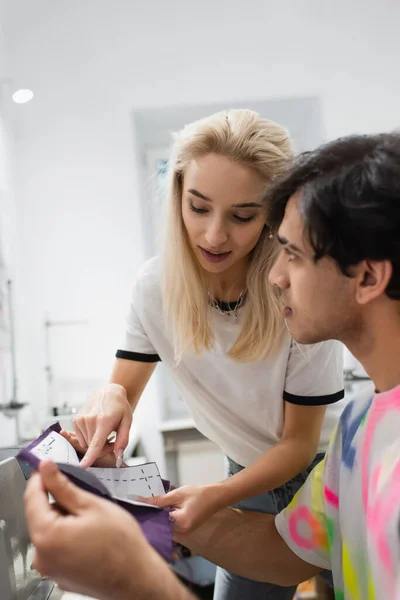 Blondynka Projektant Wskazując Wzór Szycia Pobliżu Kolegi Atelier — Zdjęcie stockowe