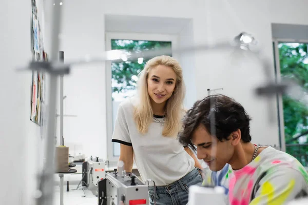 Designer Sorrindo Olhando Para Câmera Perto Alfaiate Trabalhando Primeiro Plano — Fotografia de Stock