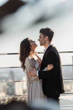 Gülümseyen adam ve mutlu kadının yan görünüşü. Lokantanın terasında kucaklaşırken birbirlerine bakıyorlar. 